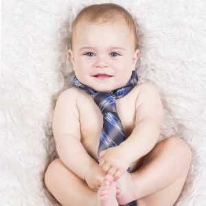 A smiling baby with a tie, lying on a soft, fluffy surface, representing sales milestones and the excitement of a "Sale is Live" event. Perfect for promoting timely sales offers and engaging audiences.