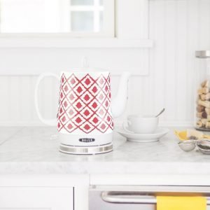 Vintage electric tea kettle with red and white geometric pattern on a kitchen countertop.