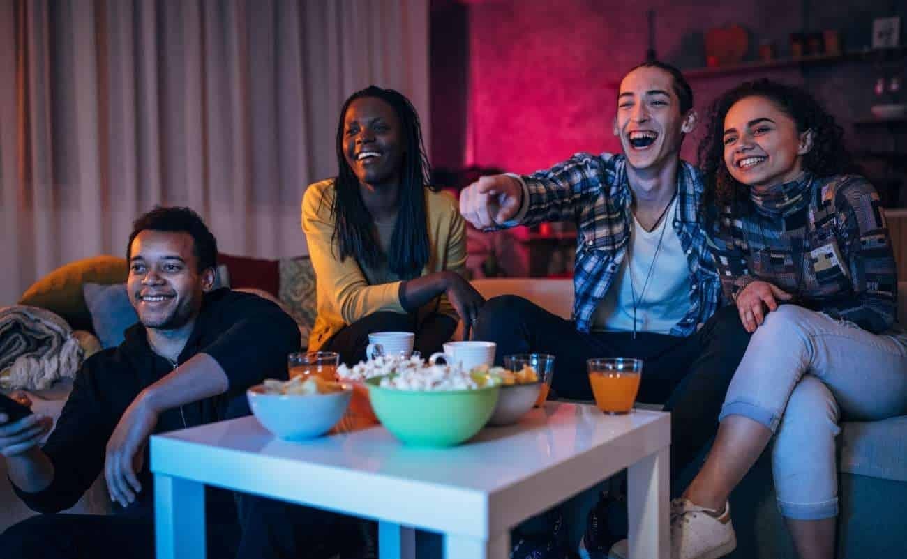 Brightly lit group of friends enjoying a fun movie night with snacks and drinks, capturing the excitement and social vibe of a home entertainment sale event.