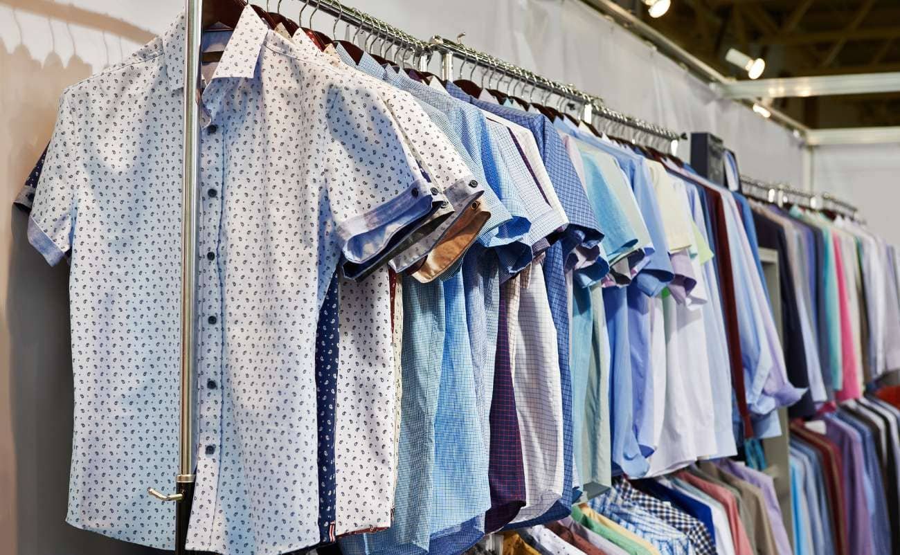 Men's casual and dress shirts on display at a clothing sale or store.