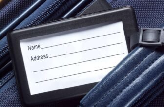 Luggage tag with name and address details on travel bag during flight or trip.