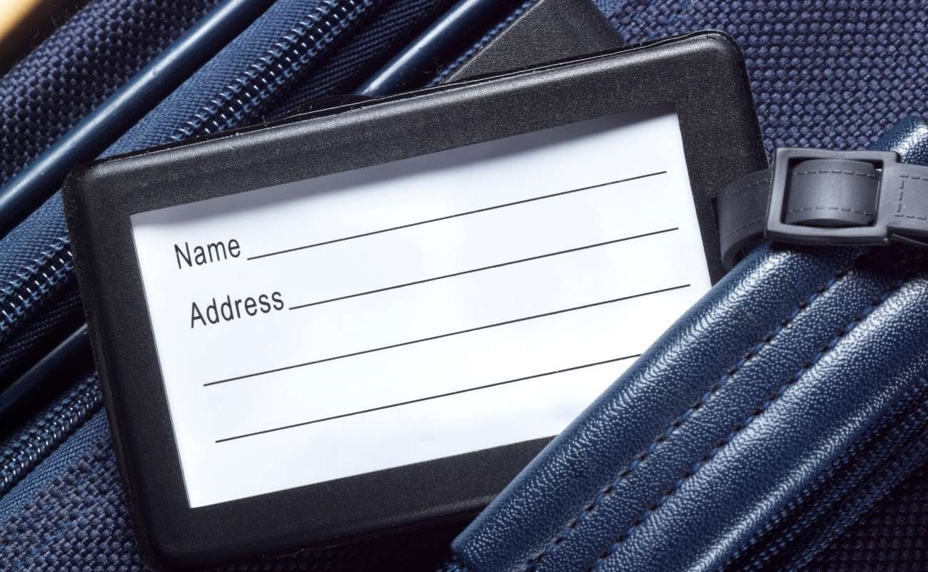 Luggage tag with name and address details on travel bag during flight or trip.