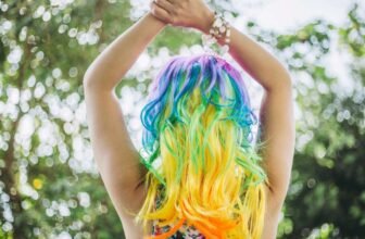 Vibrant rainbow-colored hair showcased outdoors, emphasizing bold hair dye trends and creative hair styling for fashion-forward individuals.