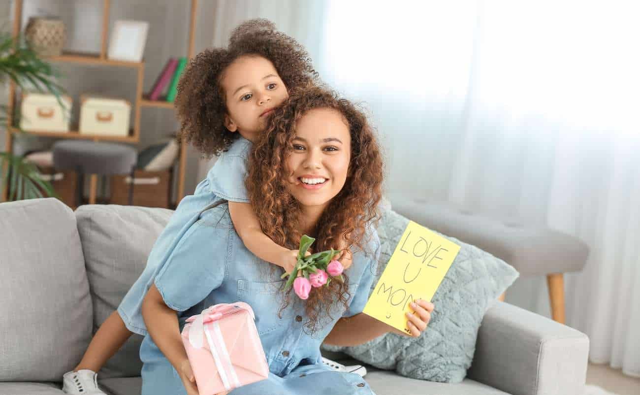 Flowers for mom, mother’s day gift, gift box, love you mom, woman with daughter, happy mother’s day, heartfelt gift, mother and daughter bond, celebration, themed gift, family love, modern home decor, cozy living room, gift for mom, seasonal gift, emotional moment, special occasion, smiling woman, daughter giving gift, cheerful atmosphere.