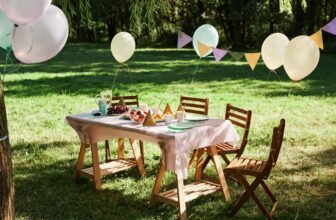 Colorful outdoor birthday party setup on a sunny garden lawn with decorated table, balloons, and party favors.