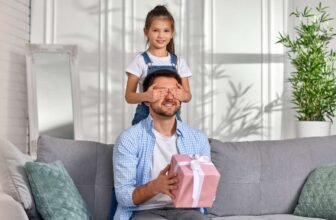 Colorful gift box being handed to a happy man by a young girl in a cozy living room during Sale is Live event.