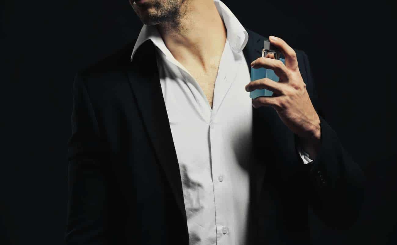 Beautifully dressed man in a black suit holding a glass of whiskey against a dark background, emphasizing luxury and elegance for exclusive sale events.