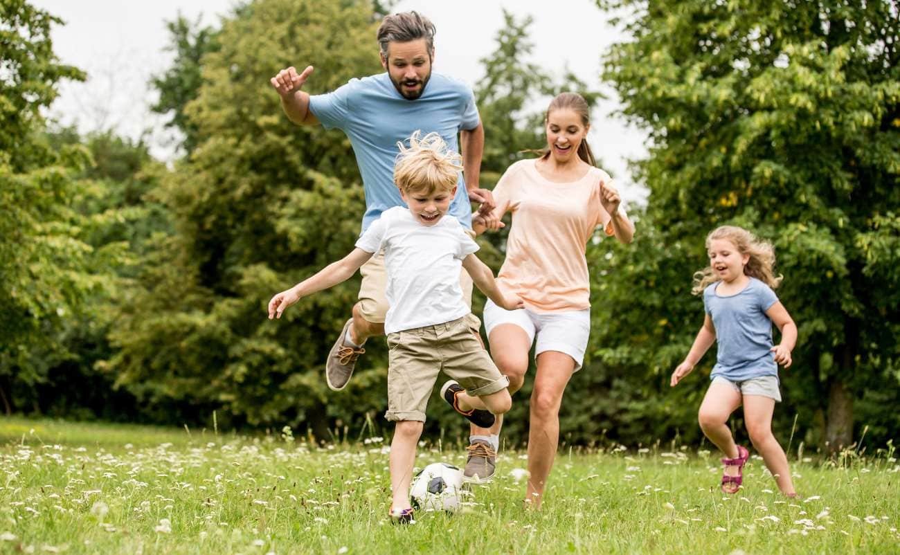 Family enjoying outdoor soccer game in a lush green park during daytime. Kids and parents playing together, capturing joyful moments of family fun and active lifestyle. Perfect for promoting outdoor activities and family entertainment.