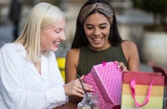 Excited women opening pink gift boxes with shopping bags during a sale event, celebrating special discounts and offers.