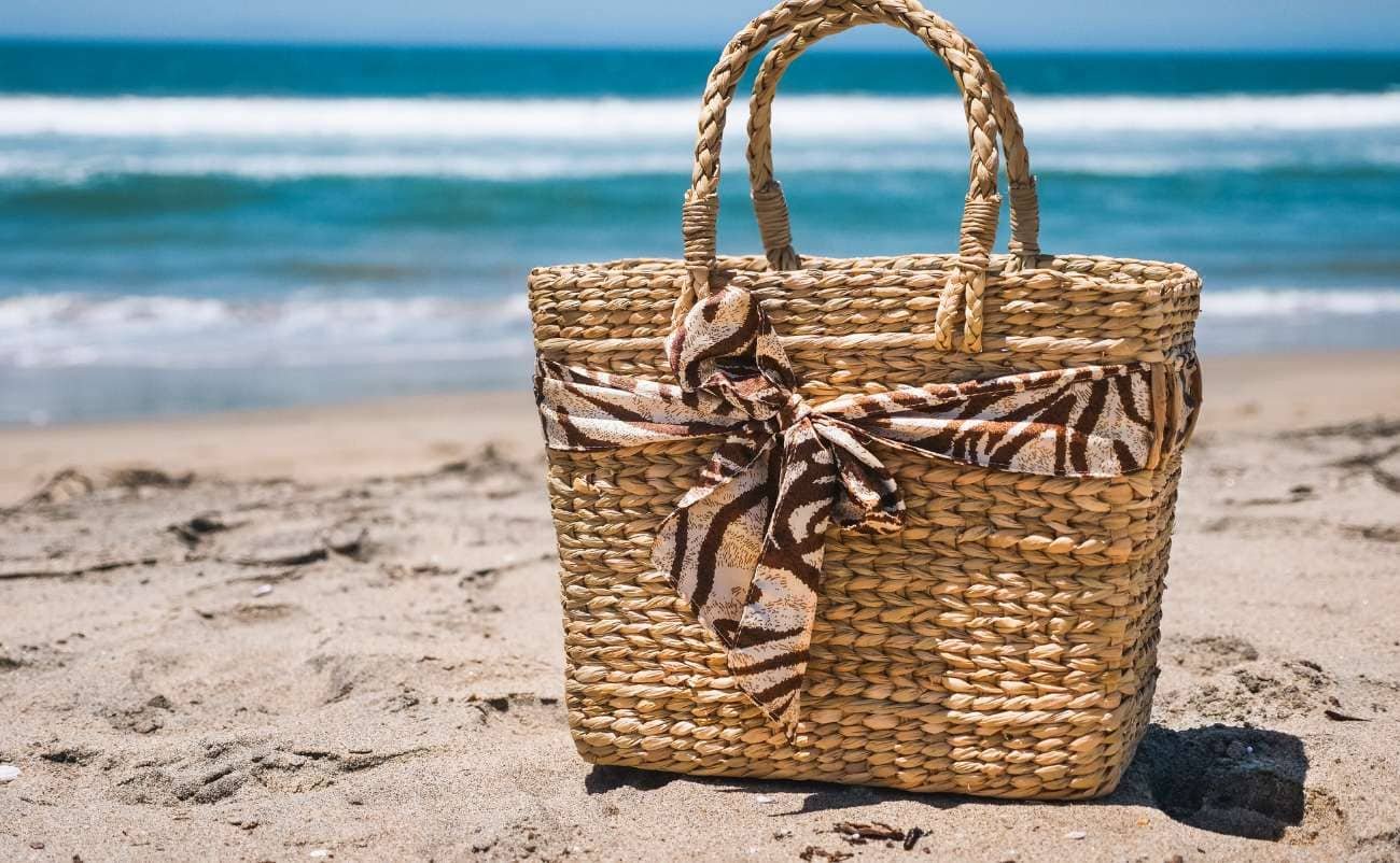 Natural woven straw beach bag with a decorative bow, perfect for summer outings and seaside shopping.