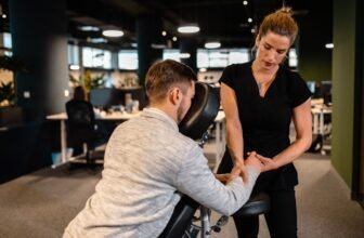 Massage therapy session in modern office environment, professional chiropractor providing treatment to male patient, health and wellness, rehabilitation, pain relief, ergonomics, workplace health.