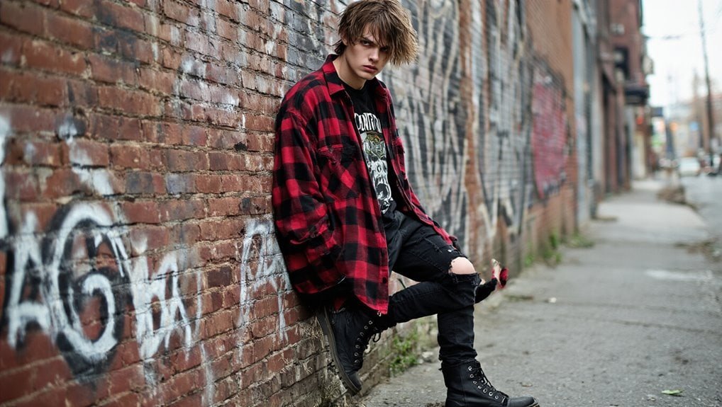 Red and black flannel shirt worn by male model on graffiti wall in urban setting.
