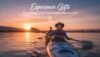 Two women kayaking on a calm lake at sunset, enjoying outdoor adventure and creating unforgettable memories with experience gifts.