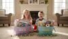Two children, a girl and a boy, happily sitting with colorful Easter baskets filled with toys and treats in a cozy living room.