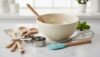 Versatile kitchen mixing bowl with wooden spoons, measuring cups, and a whisk, ideal for baking and cooking preparations.