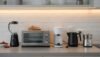 Modern kitchen countertop with a toaster, blender, coffee maker, kettle, and freshly baked bread, showcasing a clean and organized space for home cooking and baking.