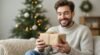Happy man holding a wrapped gift during Christmas celebration.