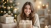 Beautiful young woman holding a wrapped gift with a Christmas tree in the background.
