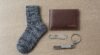 Close-up of a cozy gray sock, brown wallet, and keychain on a neutral background, ideal for gift ideas for him.