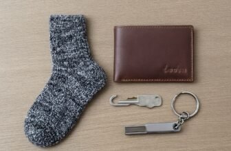 Close-up of a cozy gray sock, brown wallet, and keychain on a neutral background, ideal for gift ideas for him.