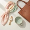 Elegant accessories including a pastel silk scarf, gold watch, ceramic mug, and a brown handbag, perfect for Mother's Day gifts for fashionable moms.